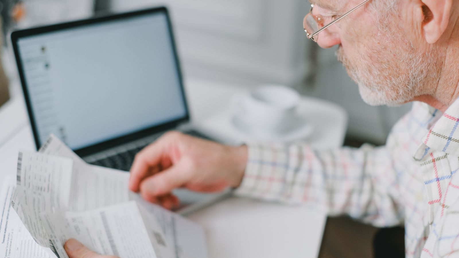 Homme consultant des documents devant un ordinateur portable à son domicile