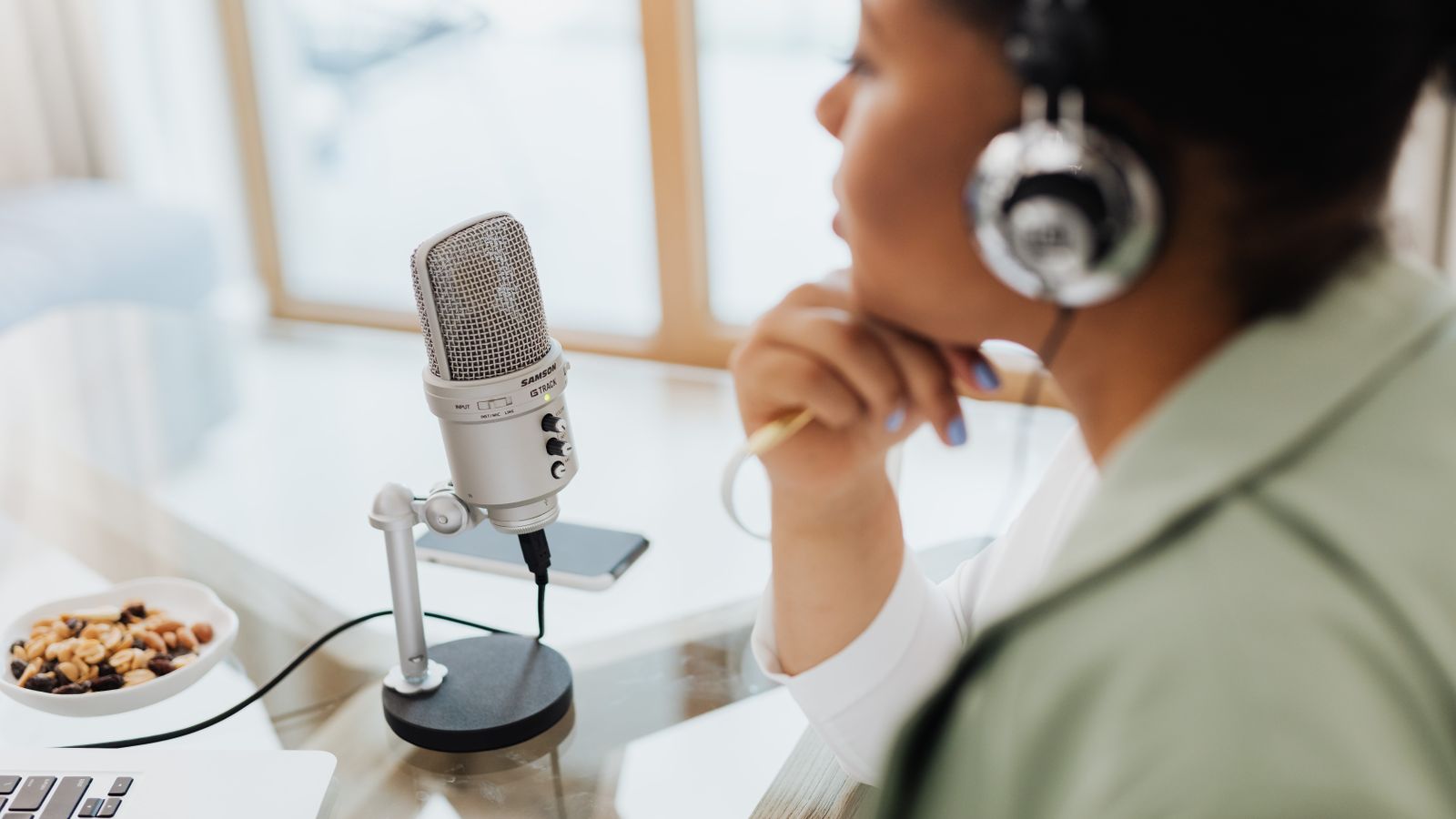 Femme installée chez elle devant un micro et un ordinateur pour enregistrer un podcast