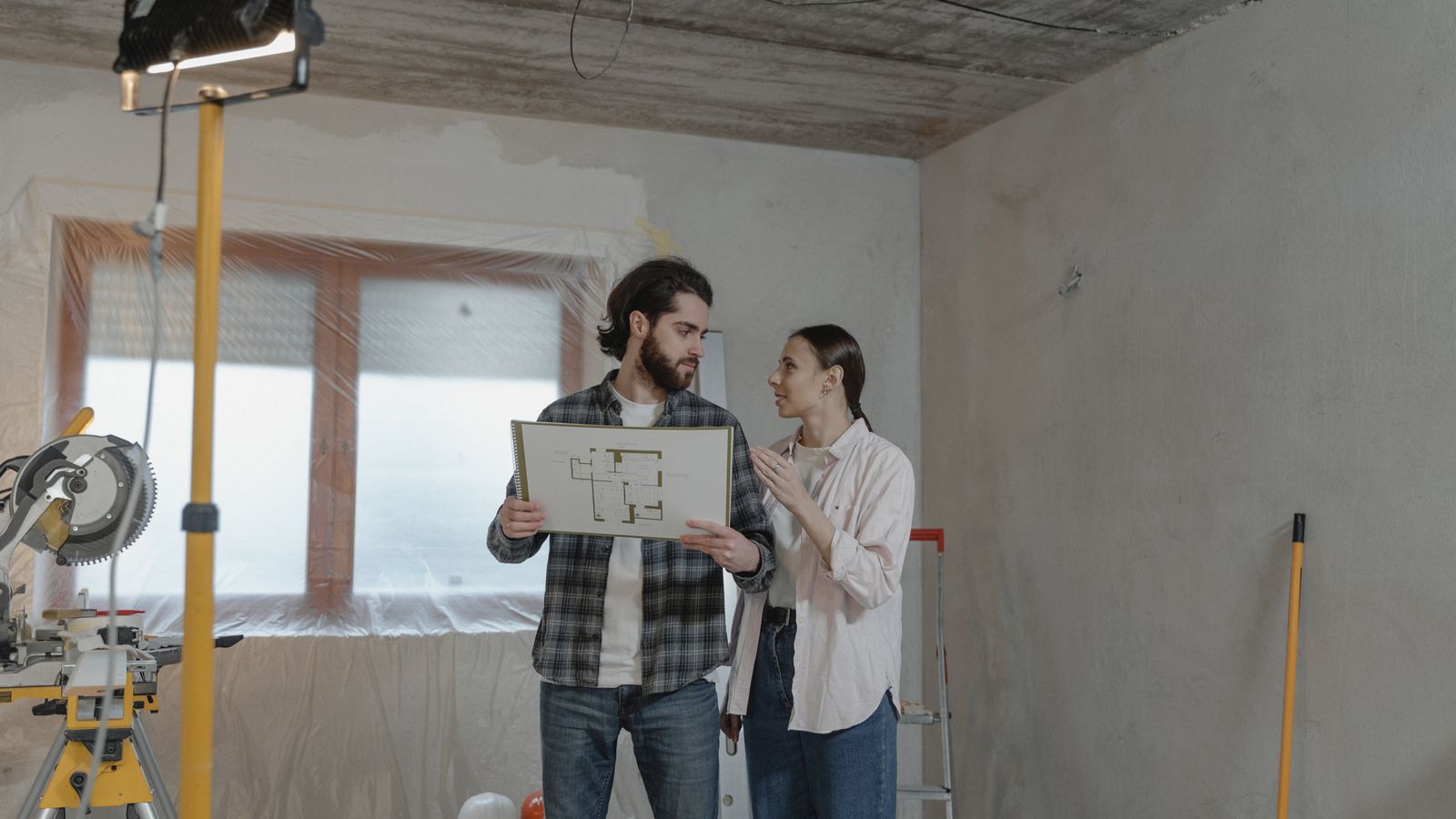 Couple examinant des plans dans une pièce en rénovation