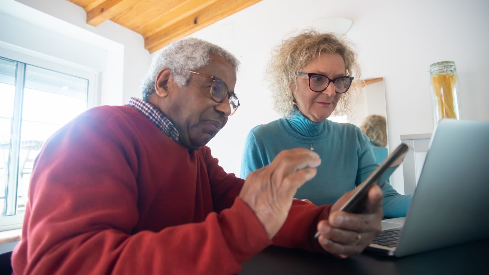 Couple consultant une annonce en ligne sur un ordinateur portable à la maison