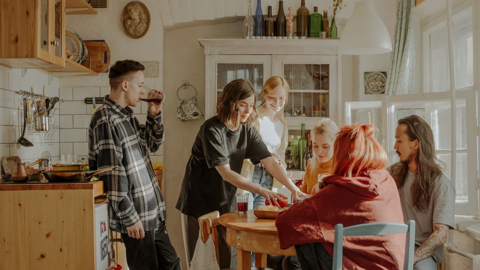 Amis réunis dans une cuisine lumineuse autour d’un repas préparé ensemble