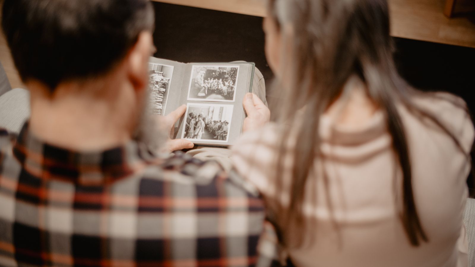 Couple feuilletant un album photo de famille dans un salon