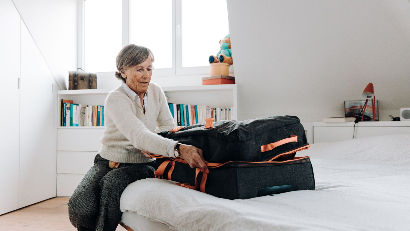 Femme préparant une valise dans une chambre lumineuse avant un long séjour