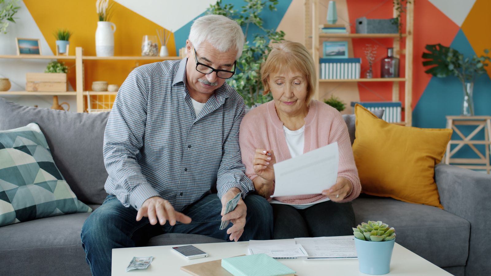 Couple âgé examinant des documents financiers dans un salon