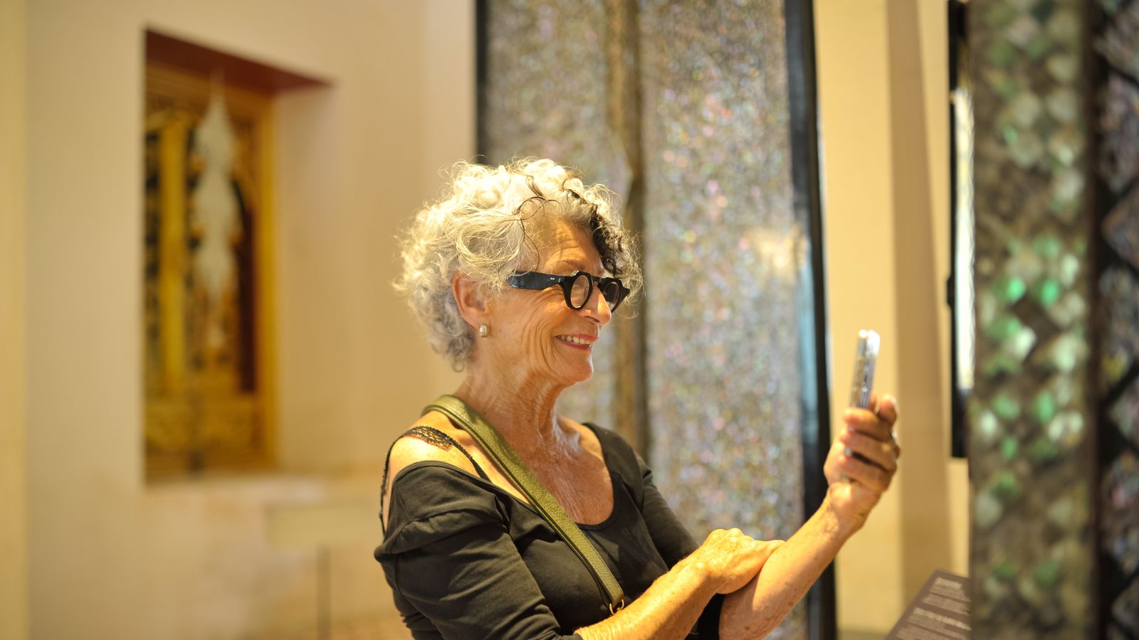 Femme photographiant une oeuvre dans un musée avec son smartphone