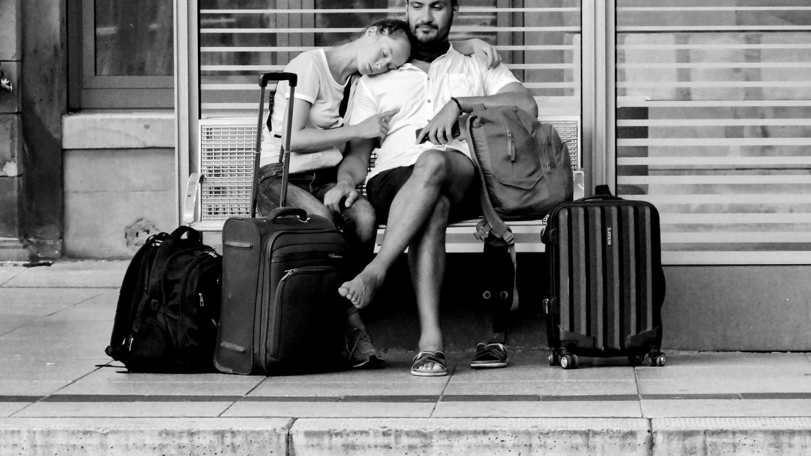 Deux voyageurs avec bagages attendent un train sur un quai de gare