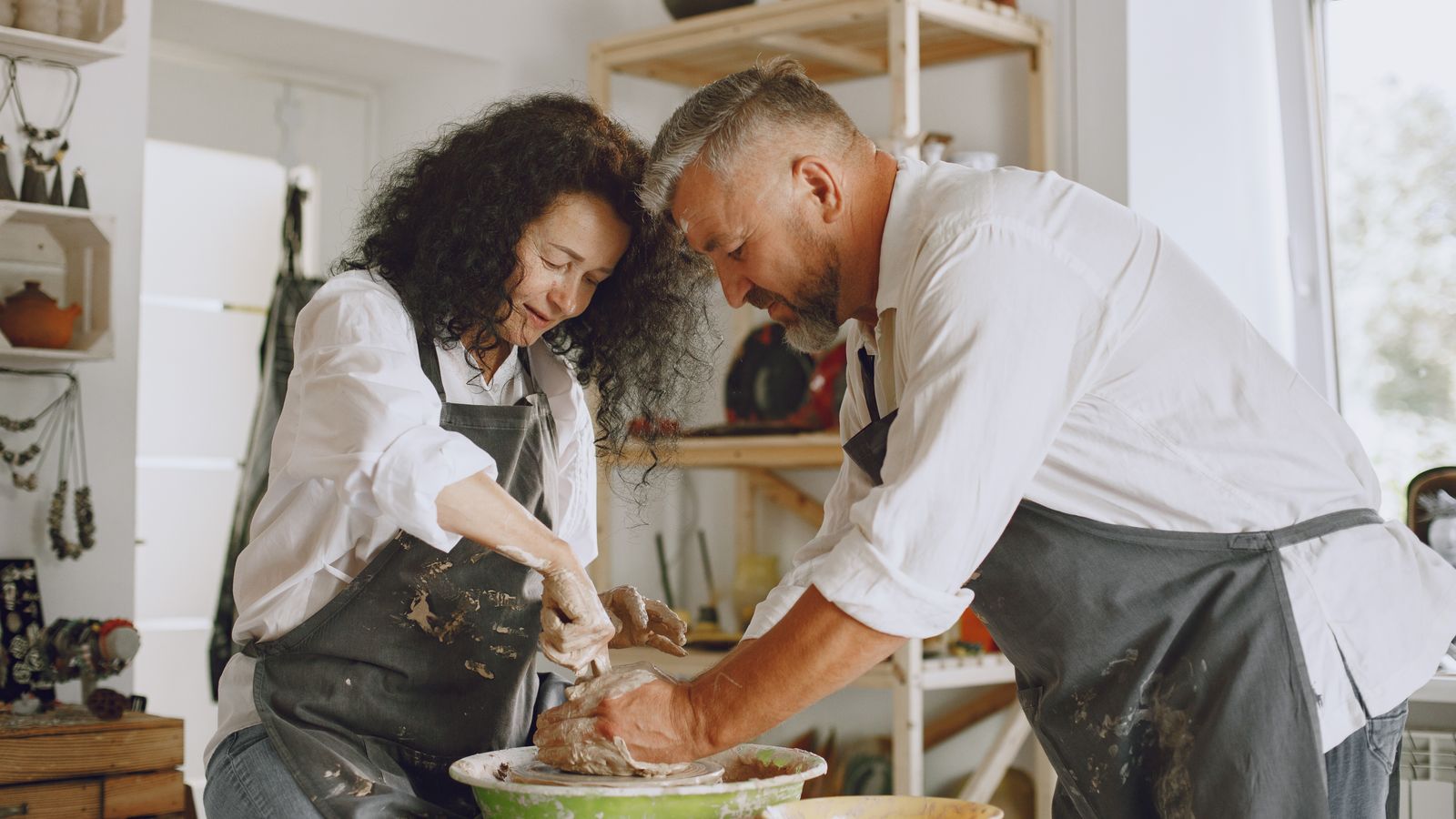 Deux adultes préparent un atelier de poterie dans une pièce lumineuse