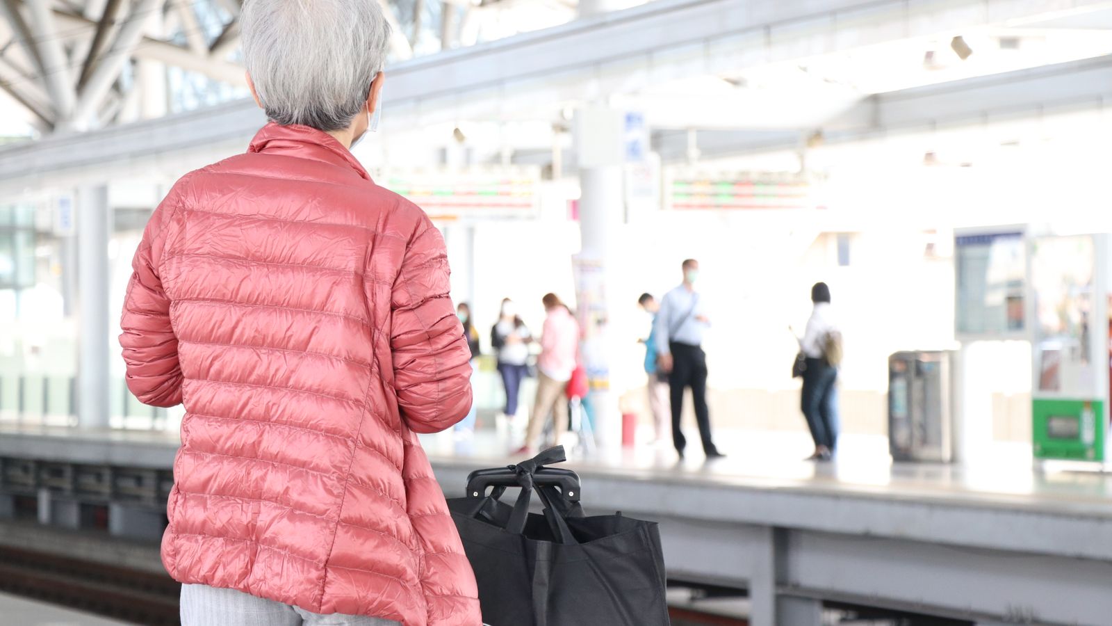 Femme senior avec une valise sur le quai d’une gare